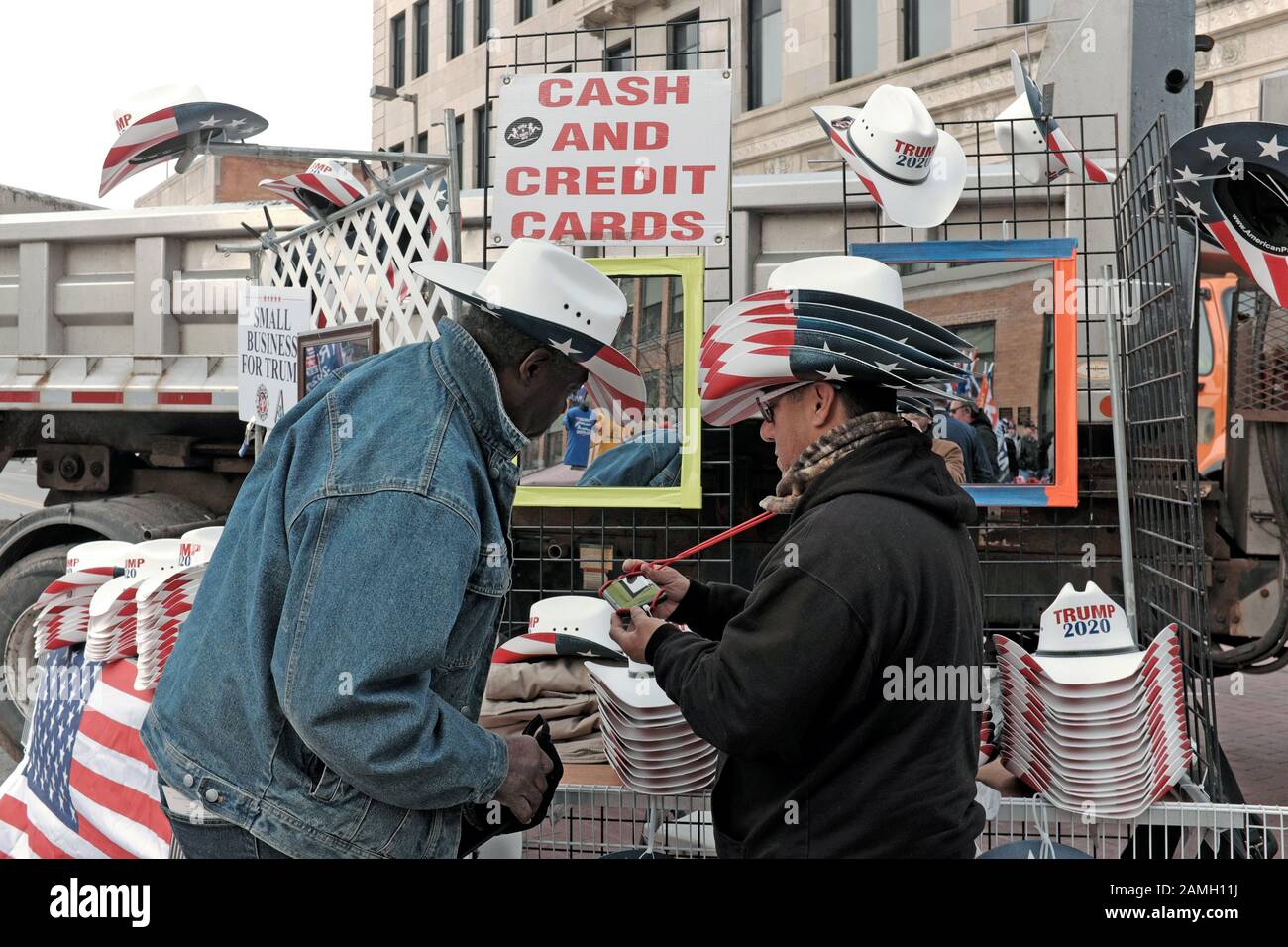 An African American Trump supporter purchases a Trump 2020 from a Hispanic vendor in Toledo, Ohio outside the Trump 2020 campaign rally. Stock Photo