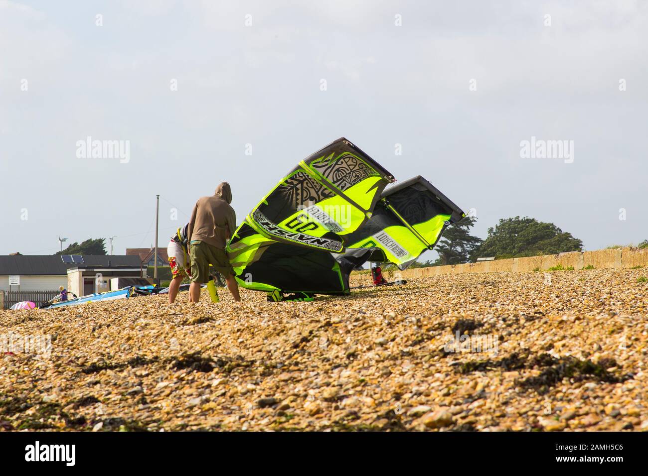 9 June 2017 A couple of young men struggle against a stiff breeze to prepare their para glider for an afternoons sport at the beach in Titchfield, Ham Stock Photo