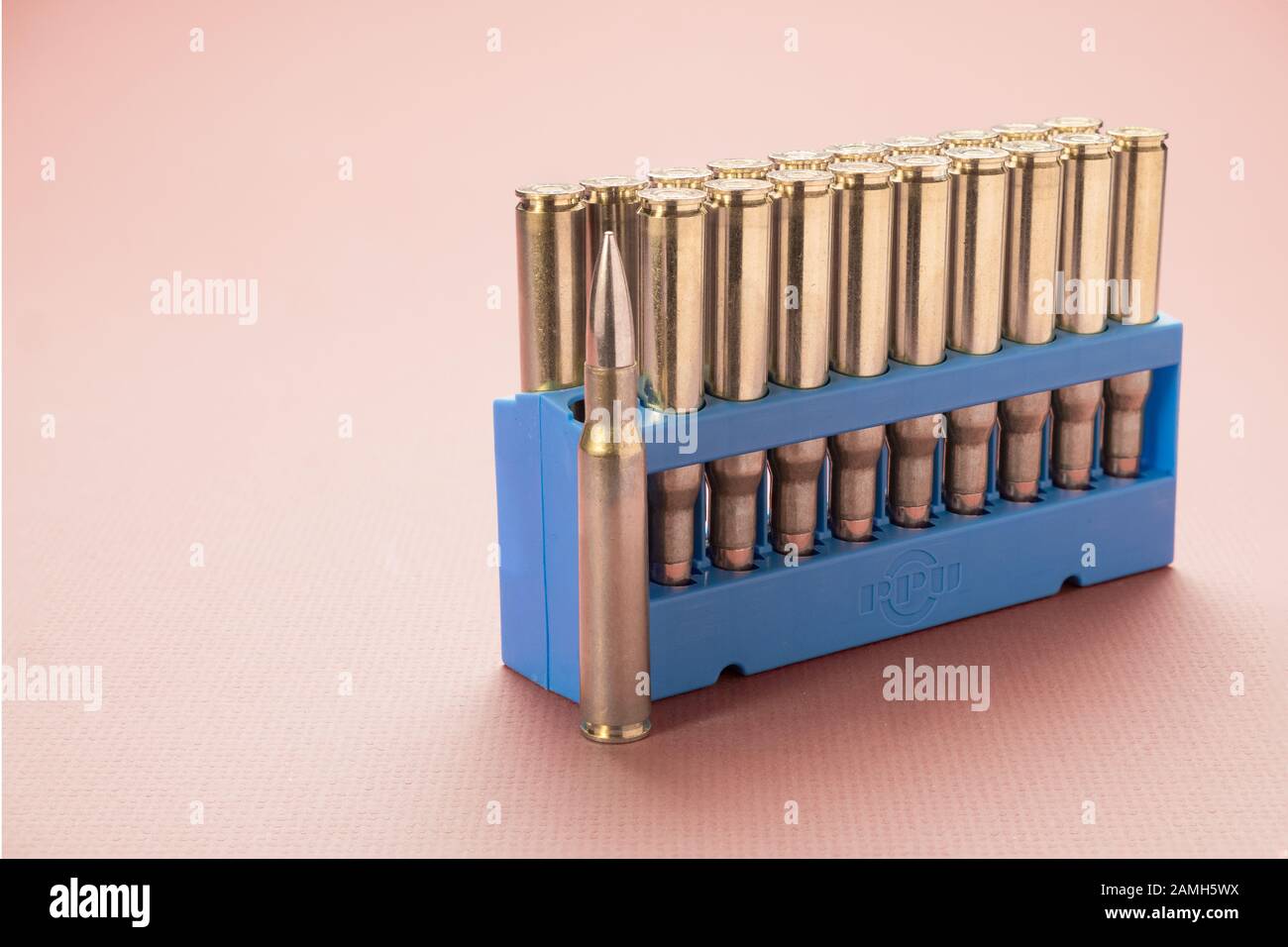 A shell holder of 30-06 Springfield centerfire rifle cartridges. One cartridge standing alone and others in cartridge shell holder. Stock Photo