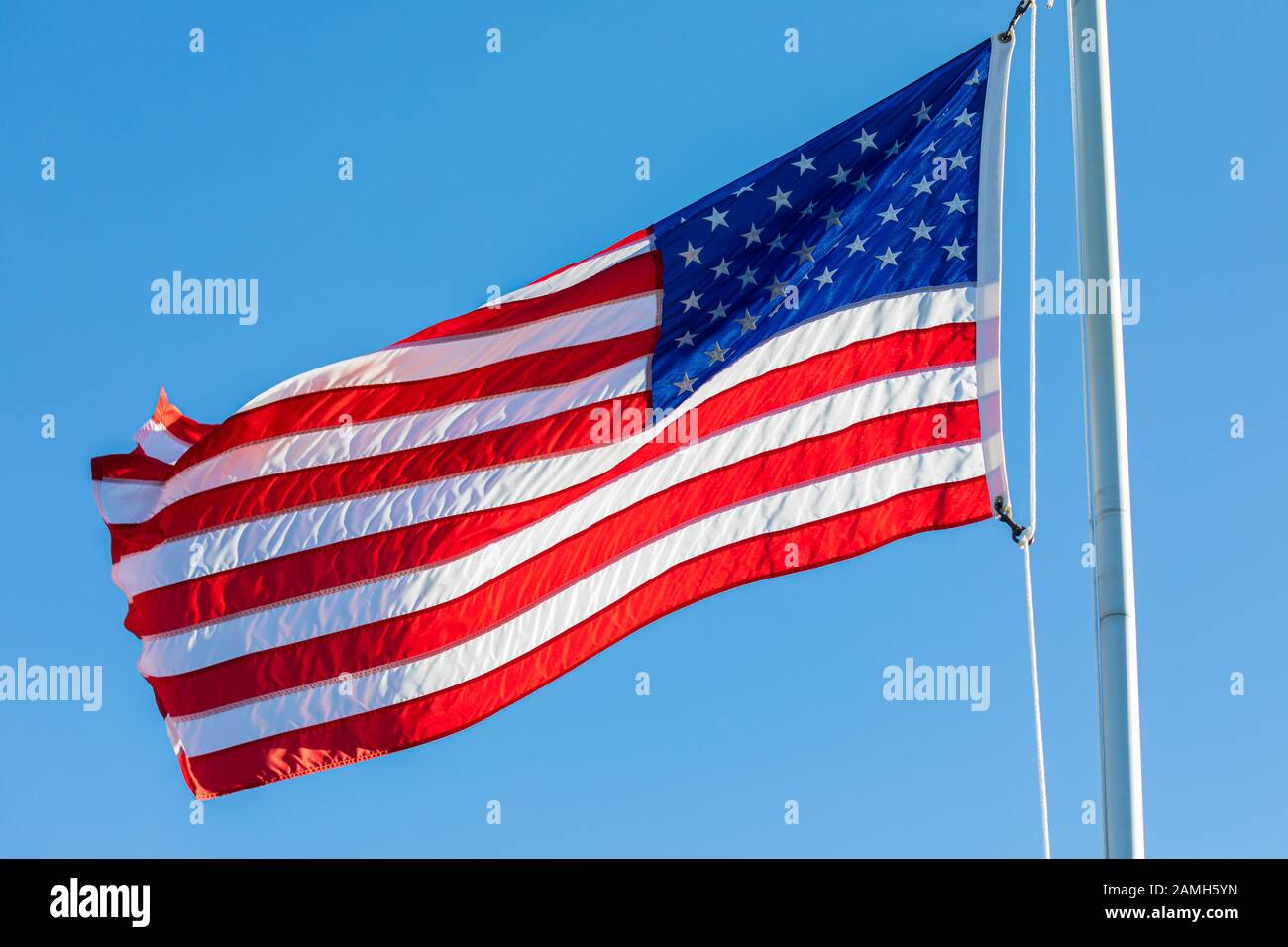 American Flag, backlit by the setting sun, waving in the wind. Stock Photo