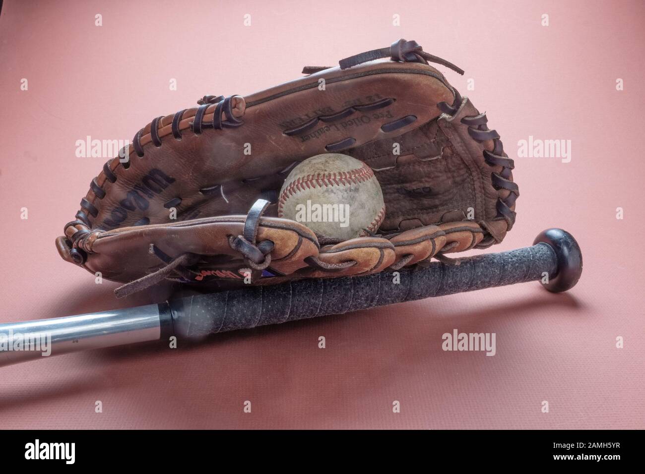 Play ball!  The great American pastime - baseball.  A leather baseball fielder’s glove, a metal baseball bat, and a play worn baseball inside the mitt Stock Photo