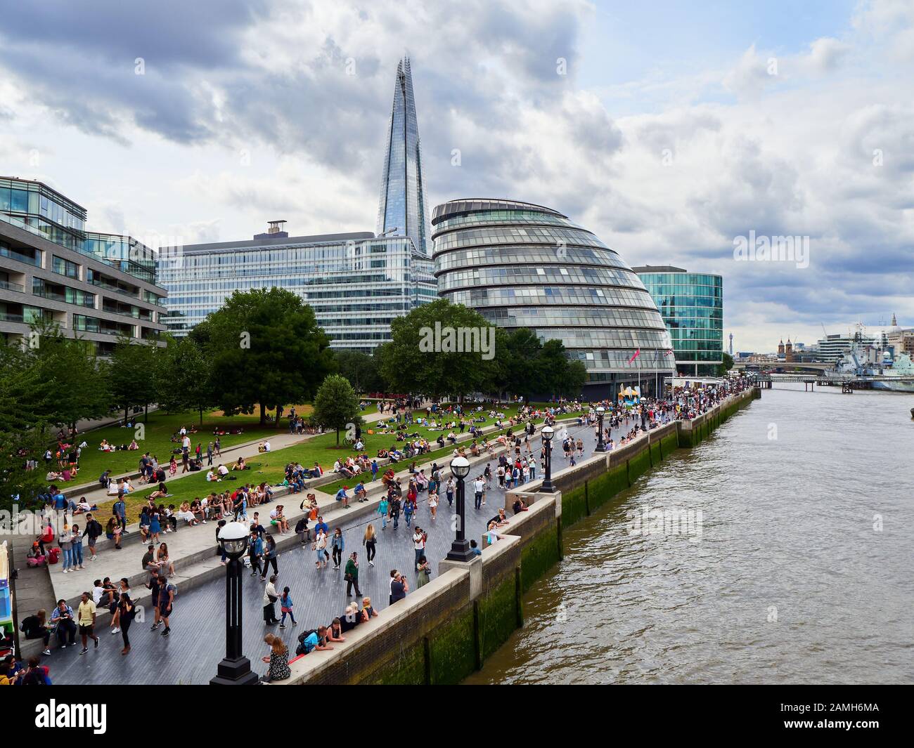 Crowds of people relaxing on the south bank next to the River Thames with The Shard in the background London Stock Photo