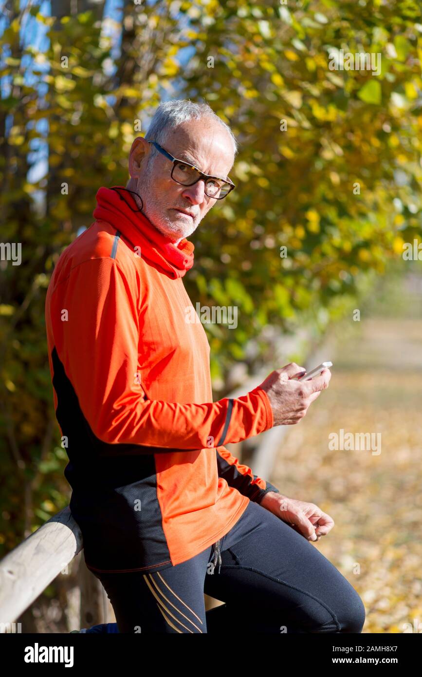 Senior runner in nature with smartphone. Stock Photo