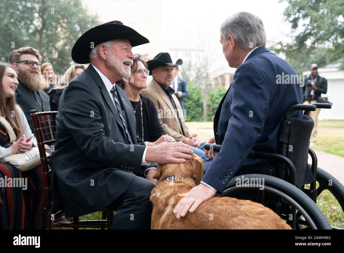 Church shooting hero Jack Wilson of White Settlement Texas (l) greets Gov. Greg Abbott and Abbott's pet golden retriever Peaches during ceremony at which Abbott presented the Governor's Medal of Courage at the Texas Governor's Mansion. Wilson, a volunteer member of the West Freeway Church of Christ's security team,shot and killed a man who opened fire with a rifle during service at the church near Fort Worth Texas last month. Stock Photo