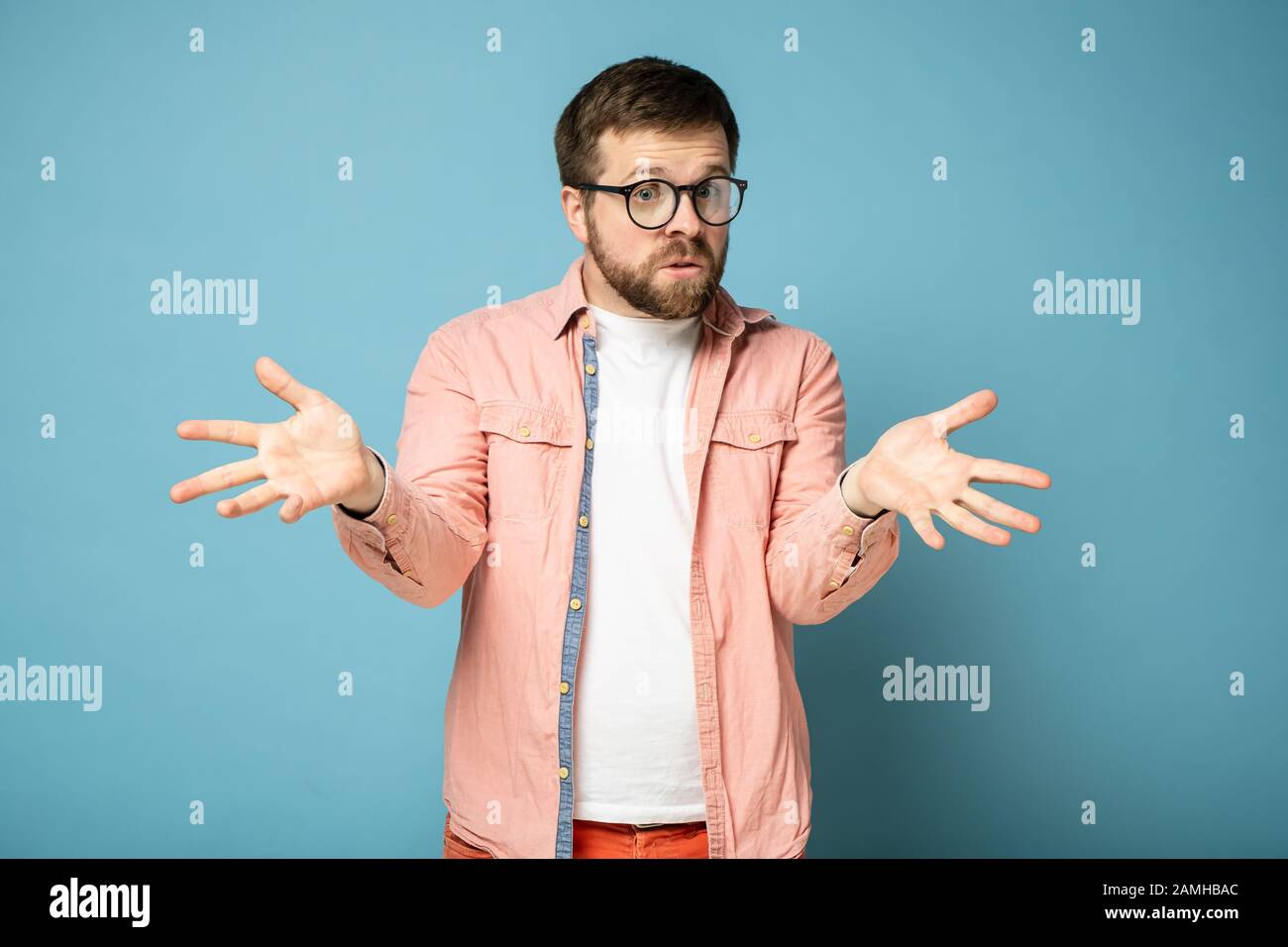 Man is excited and bewildered, he is amazed at what is happening, looks inquiringly at the camera and makes a gesture with hands. Stock Photo