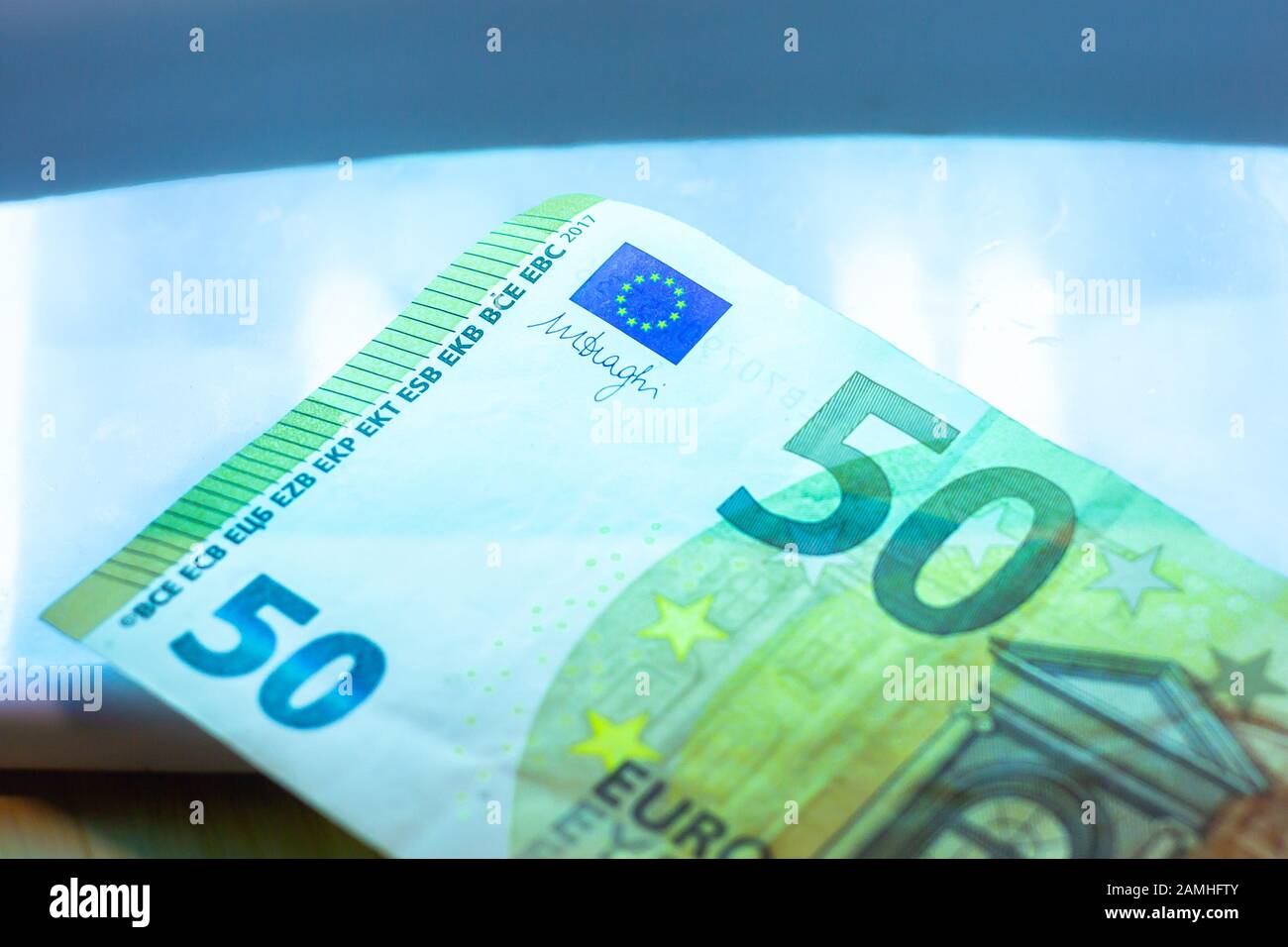 An authentication of paper euro banknotes with infrared or ultraviolet light detector. Checking of Fifty euro Stock Photo