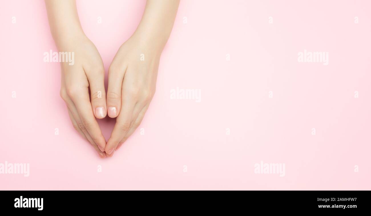 The woman hands on a pink background. Cosmetics for a sensitive skin care. Natural petal cosmetics, anti-wrinkle hand care. A thin wrist and natural Stock Photo