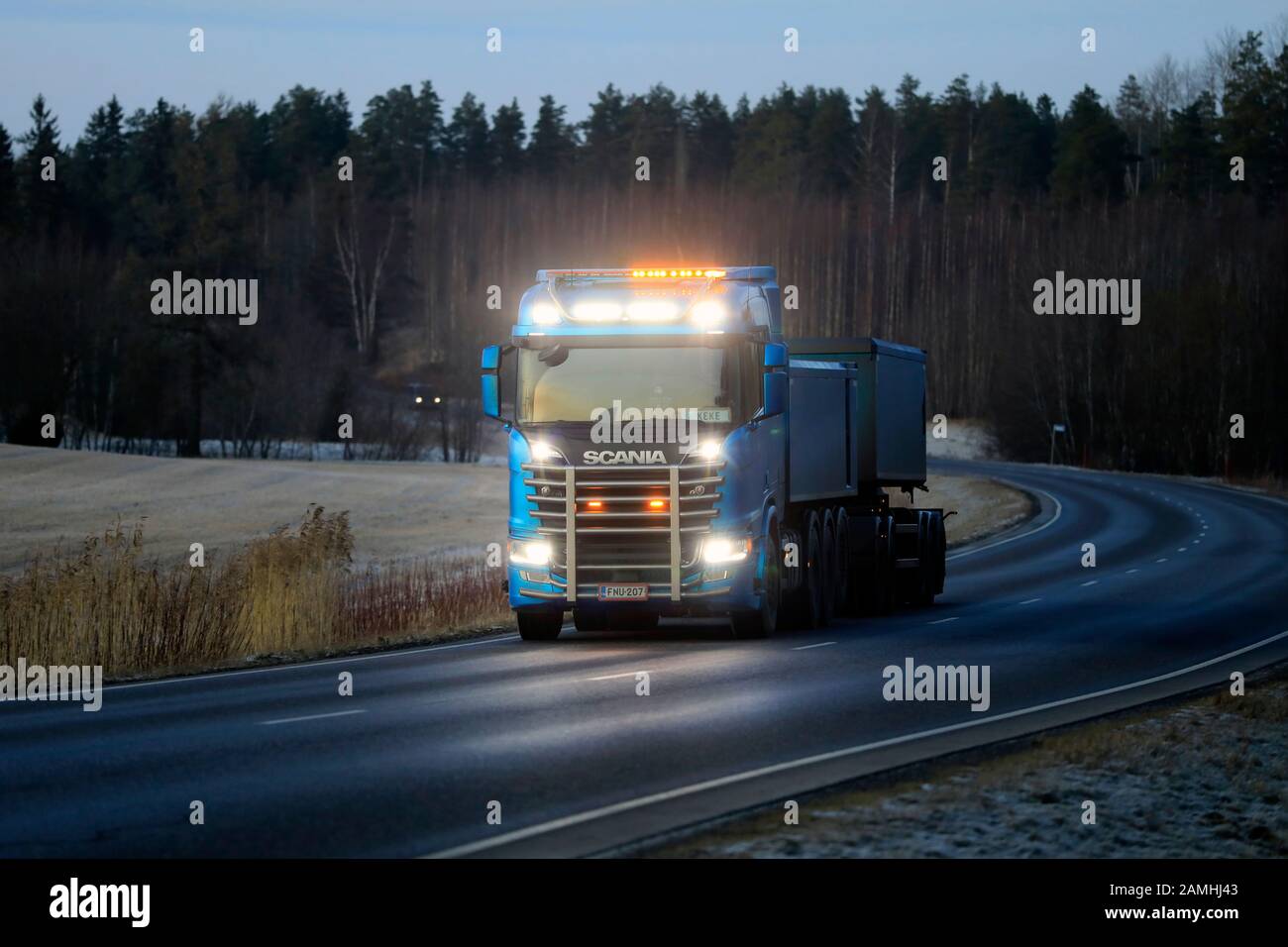 High beams of beautiful Scania R650 truck for limestone haul of Kuljetusliike Markus Hanninen light up the dark road.  Salo, Finland. Jan 10, 2020. Stock Photo
