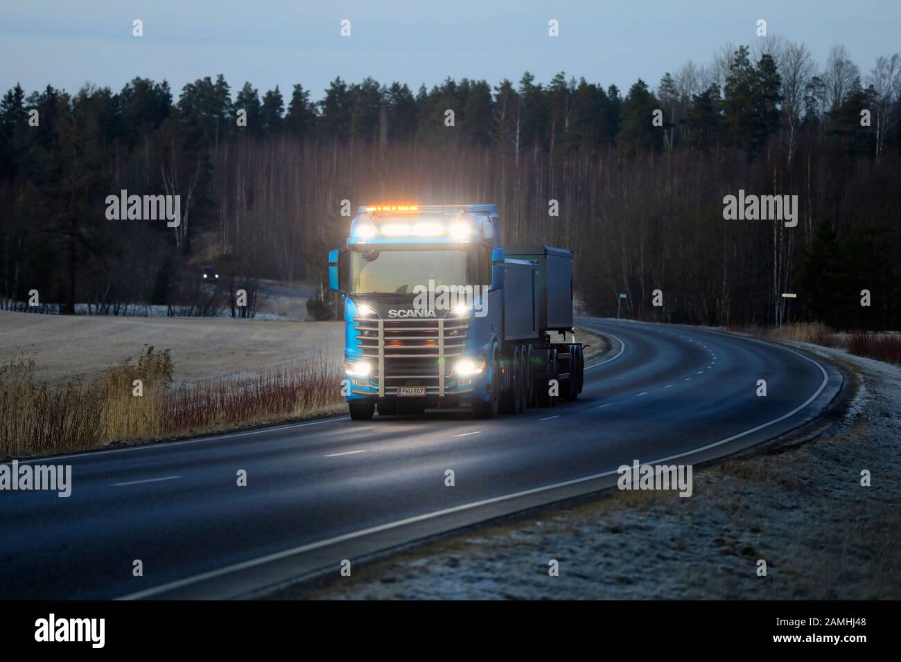 High beams of beautiful Scania R650 truck for limestone haul of Kuljetusliike Markus Hanninen light up the dark road.  Salo, Finland. Jan 10, 2020. Stock Photo