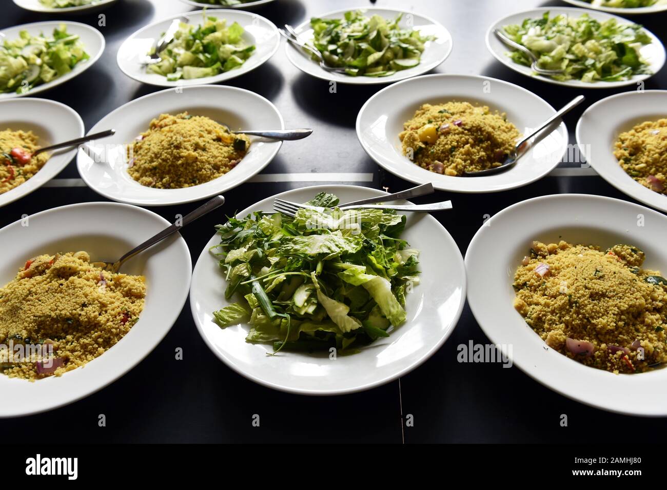 Wedding reception food is laid out ready for the table, couscous and salad in big bowls for sharing. Stock Photo