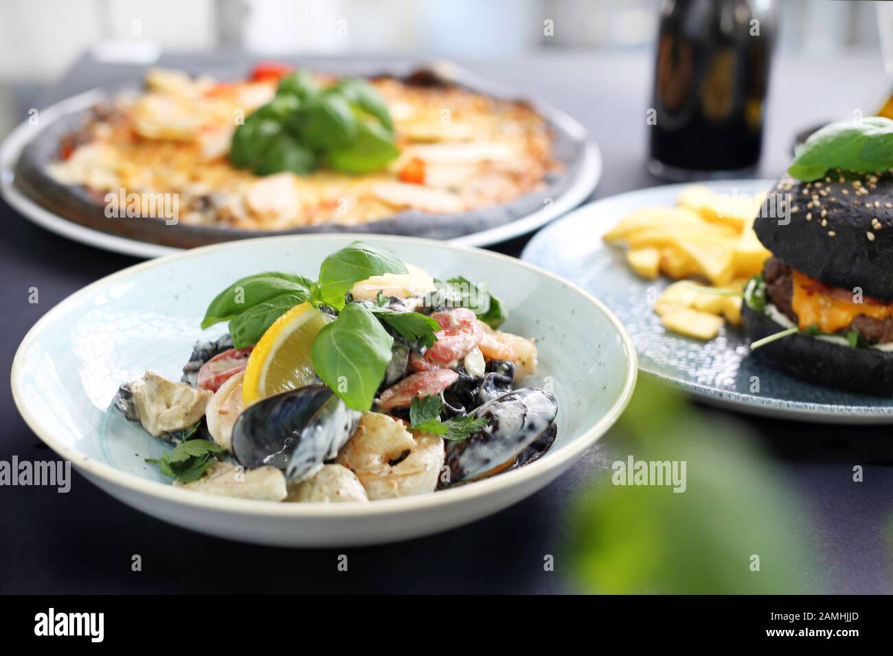 Black food. Burger, pizza, pasta, dishes with activated charcoal. Stock Photo