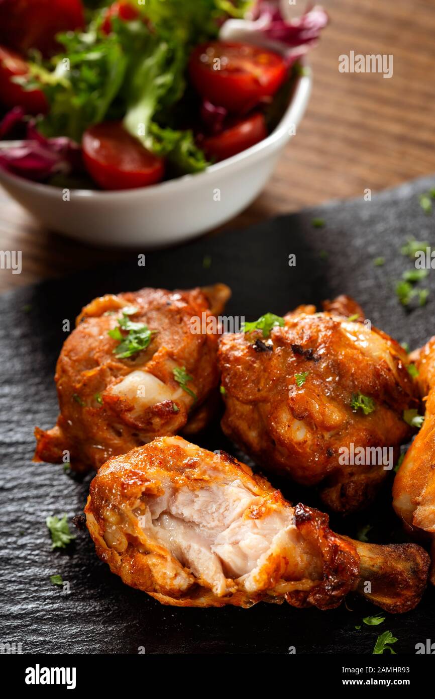 Roasted chicken drumsticks with salad on dark slate Stock Photo