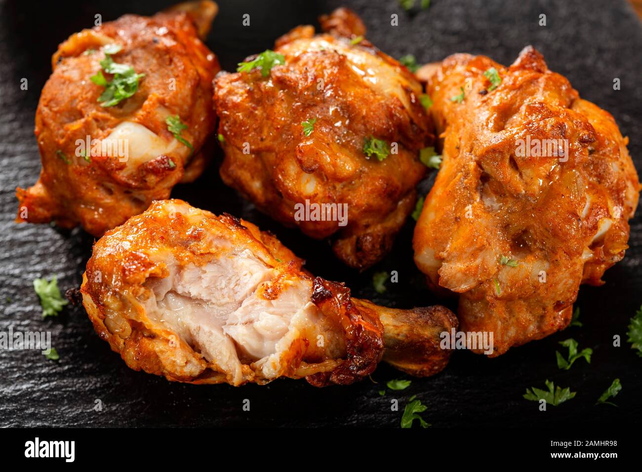 Roasted chicken drumsticks on dark slate - close up view Stock Photo