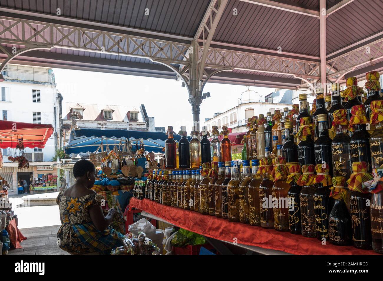 Stallholder with local crafts including wines, drinks, oils and spices at the Spice Market in Pointe-a-Pitre, Guadeloupe, West Indies, Caribbean Stock Photo