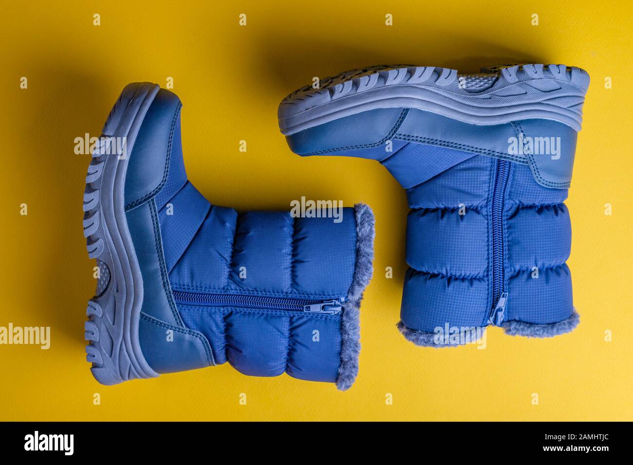 Winter water-repellent boots in blue with a gray sole on a yellow background Stock Photo