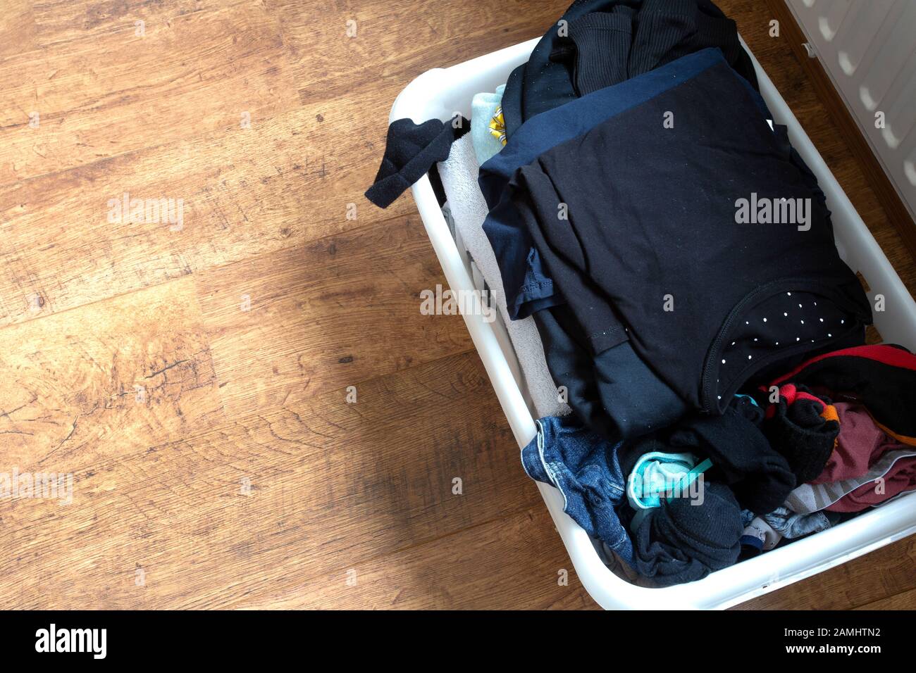 clothes in a full laundry basket on a laminaat floor, top view Stock Photo