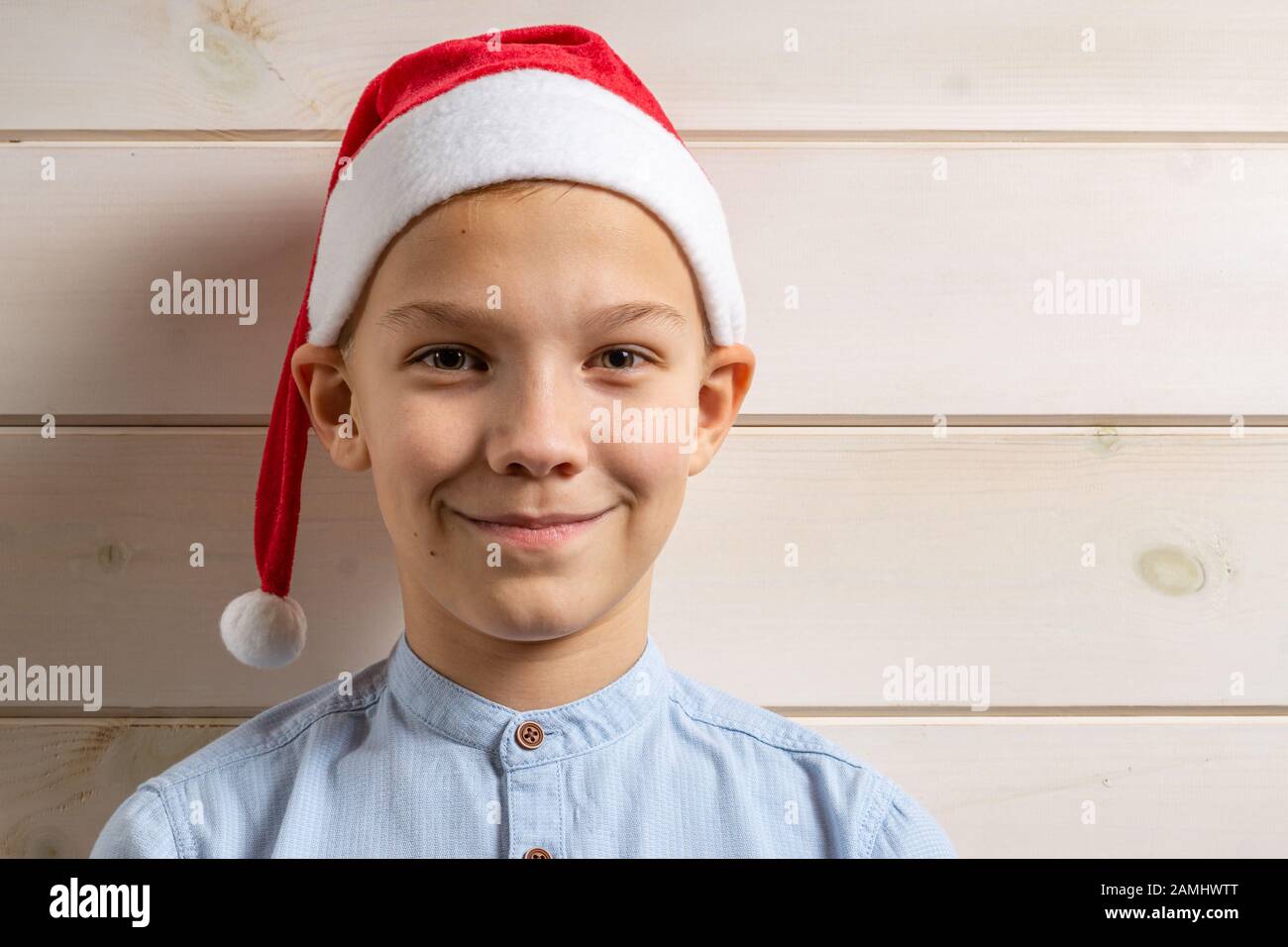 A boy of 10 years old in a blue shirt smiles on a light wooden ...