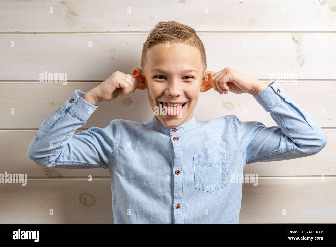 A boy of 10 years old in a blue shirt smiles on a light wooden ...