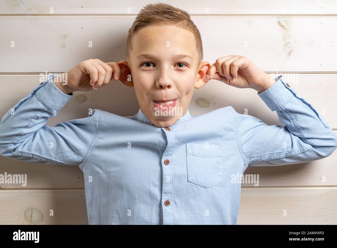 A boy of 10 years old in a blue shirt smiles on a light wooden ...