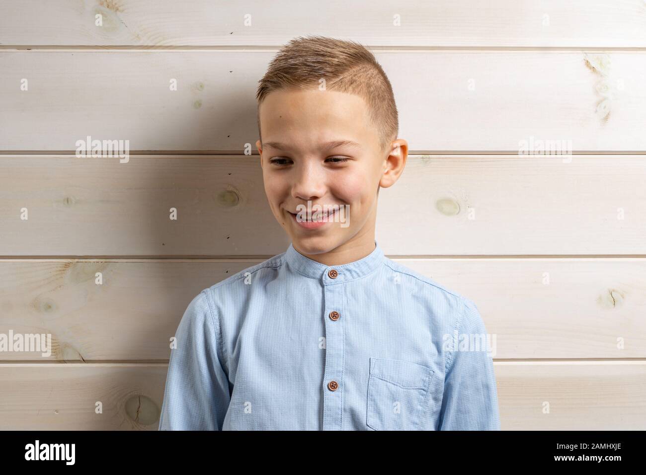 A boy of 10 years old in a blue shirt smiles on a light wooden ...
