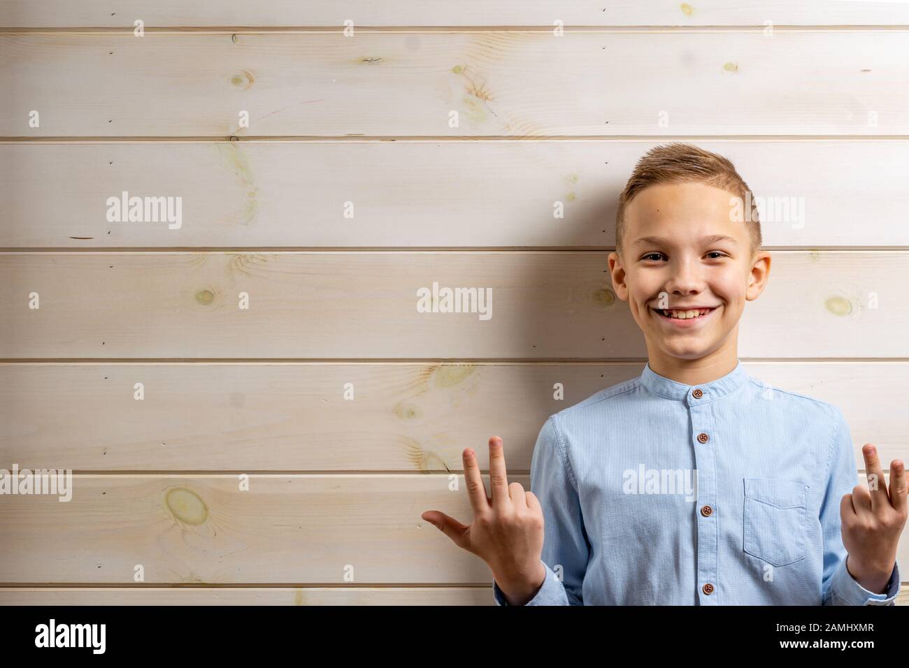 A boy of 10 years old in a blue shirt smiles on a light wooden ...