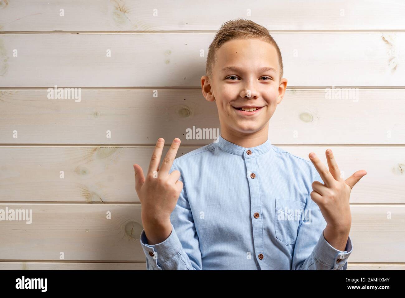 A boy of 10 years old in a blue shirt smiles on a light wooden ...