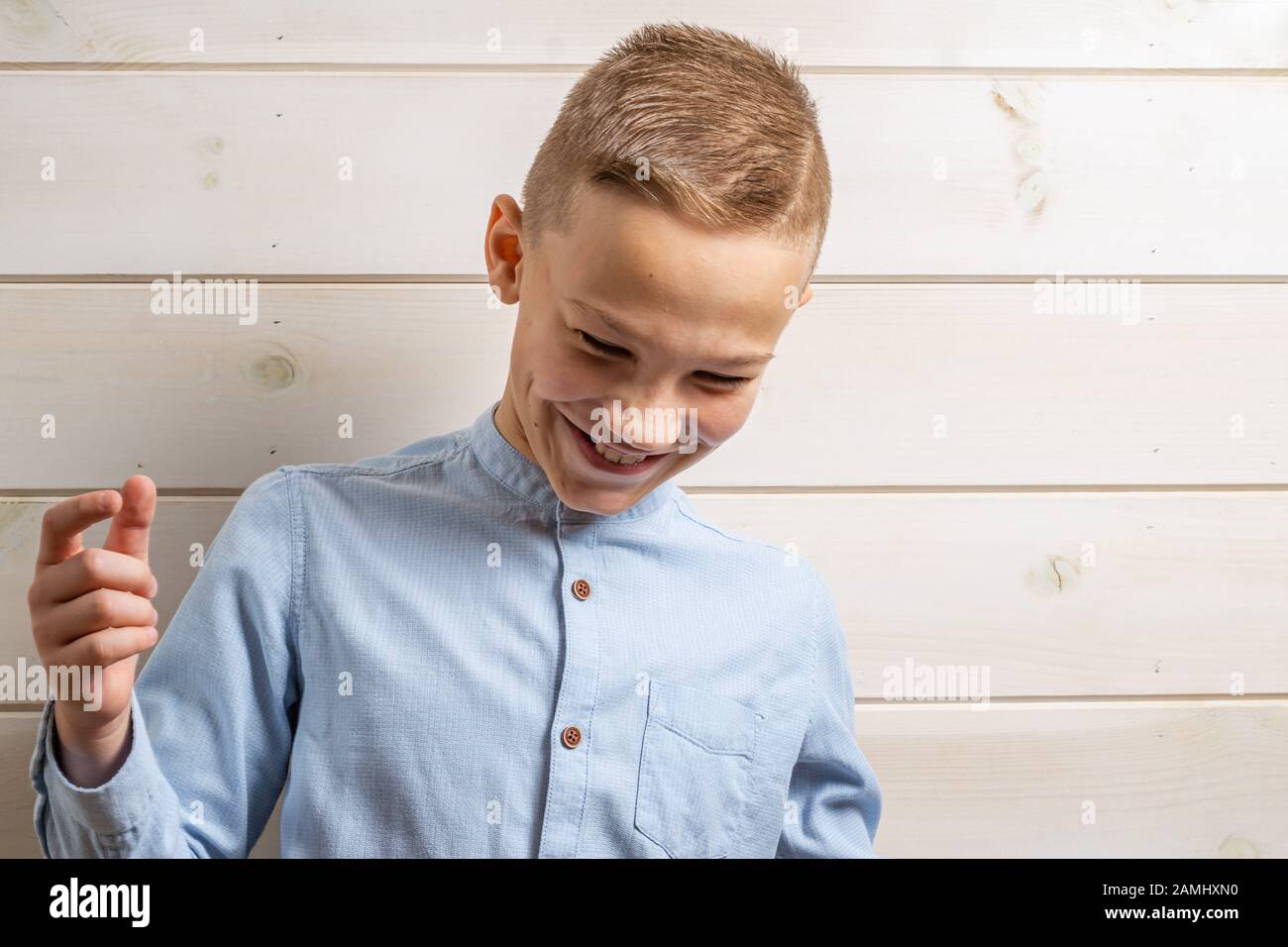 A boy of 10 years old in a blue shirt smiles on a light wooden ...