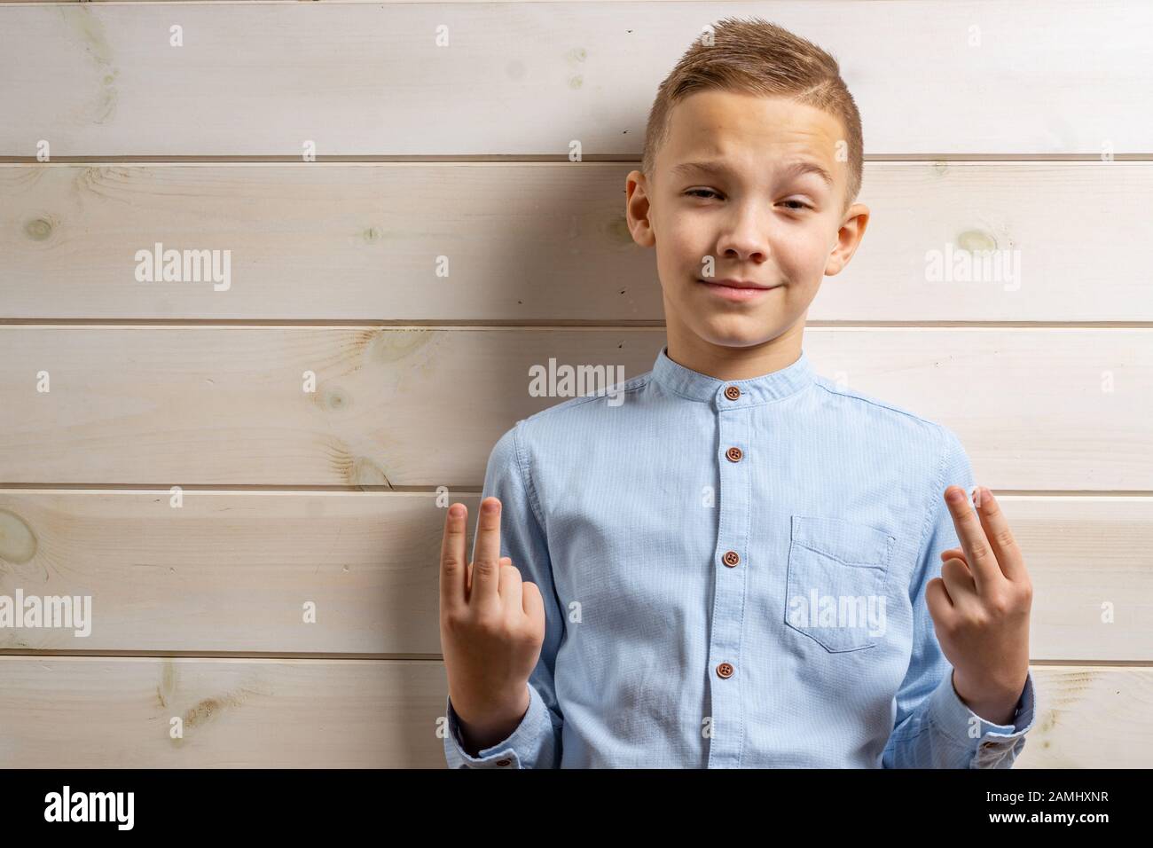 A boy of 10 years old in a blue shirt smiles on a light wooden ...