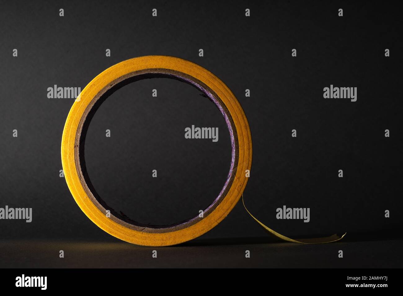 Roll of masking tape. Yellow tape. On a black background Stock Photo