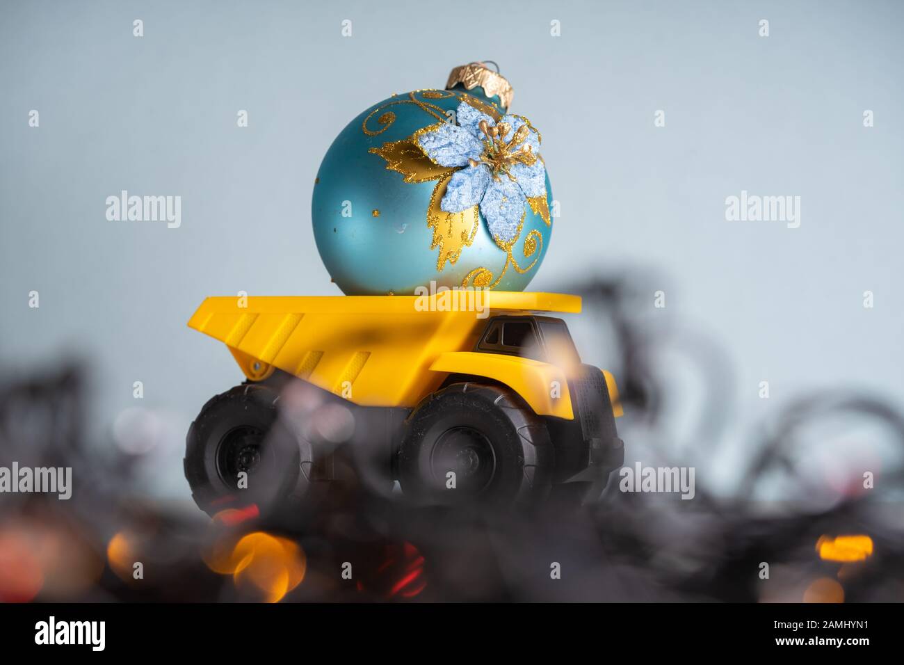 Yellow dump truck model with Christmas tree toy. Garland lights in
