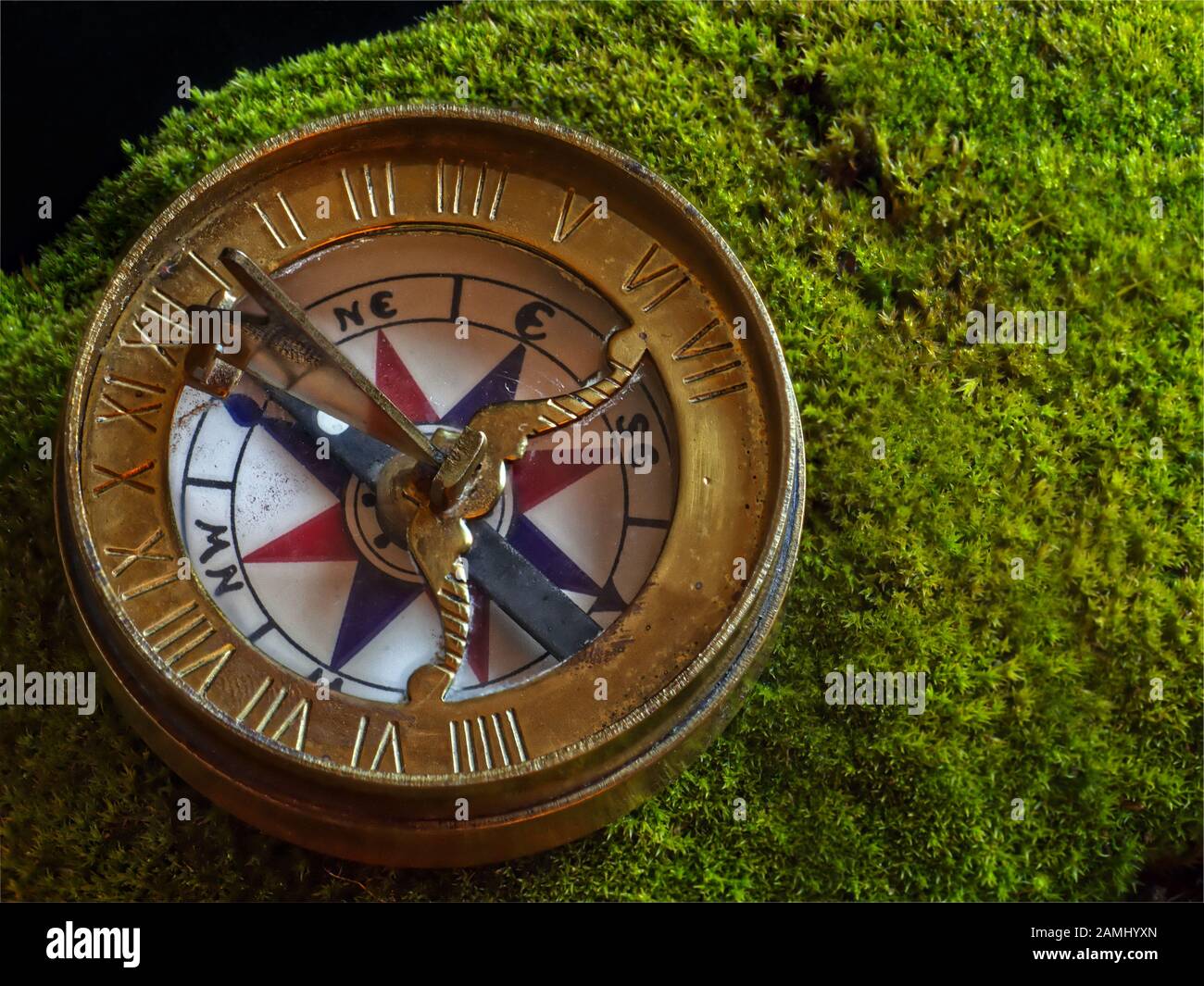 A replica of a golden 1750 era brass compass including folding sundial  "gnomon" resting on bright green moss Stock Photo - Alamy