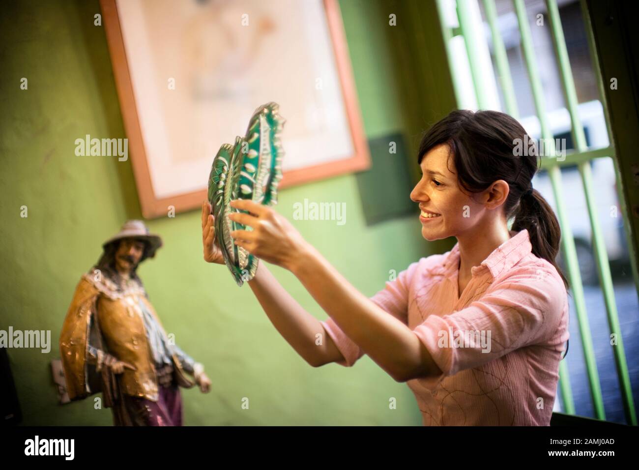 A woman thoughtfully looks at a decorative piece. Stock Photo