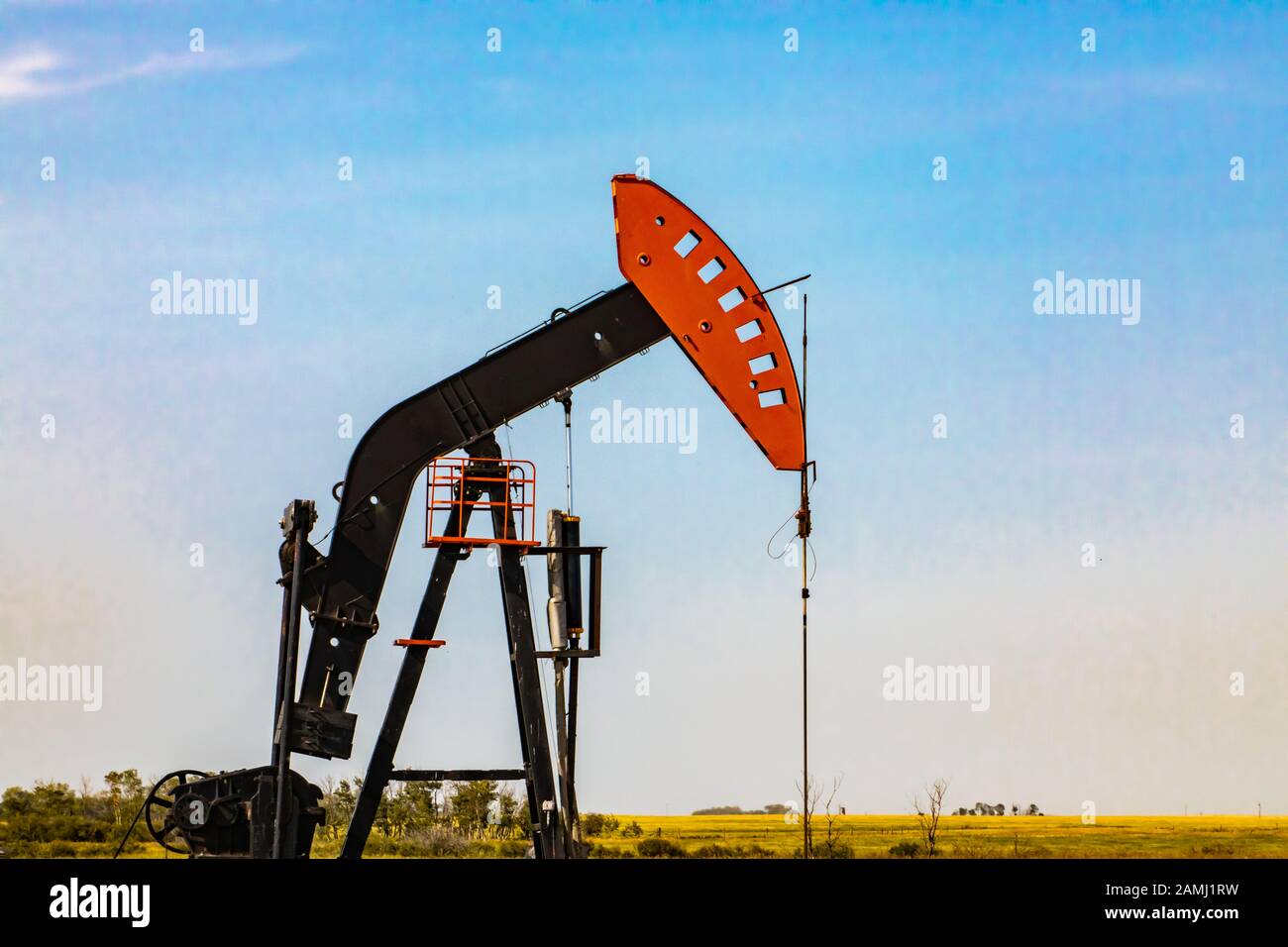 Closeup view of a pumpjack, or nodding horse head, against a pale blue