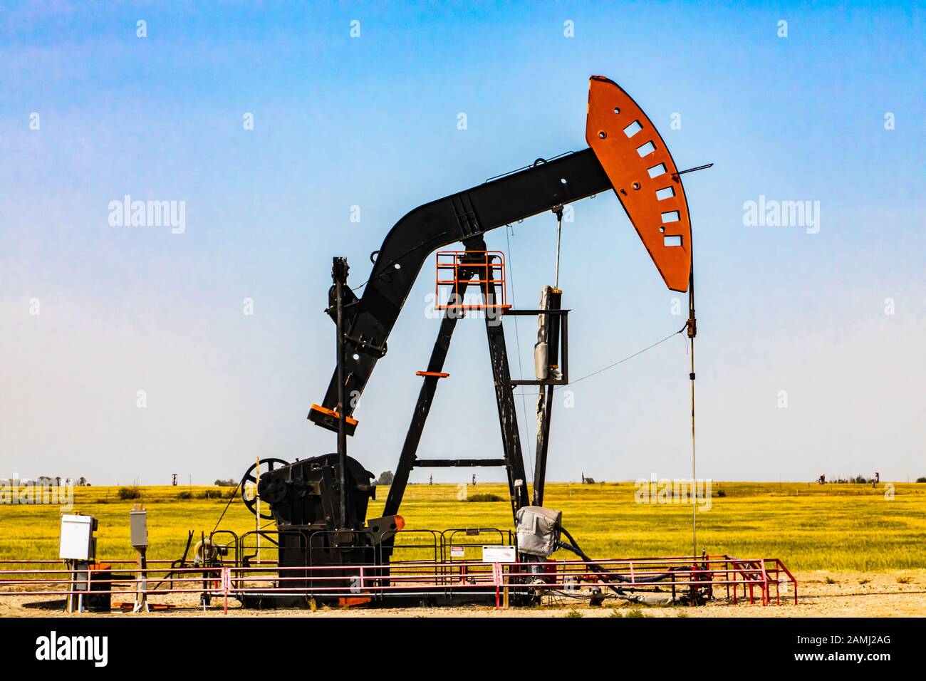 Details of a mechanical pumpjack, overground pumping apparatus of an oil well, with nodding horse head and walking beam, against a blue sky with copy space Stock Photo