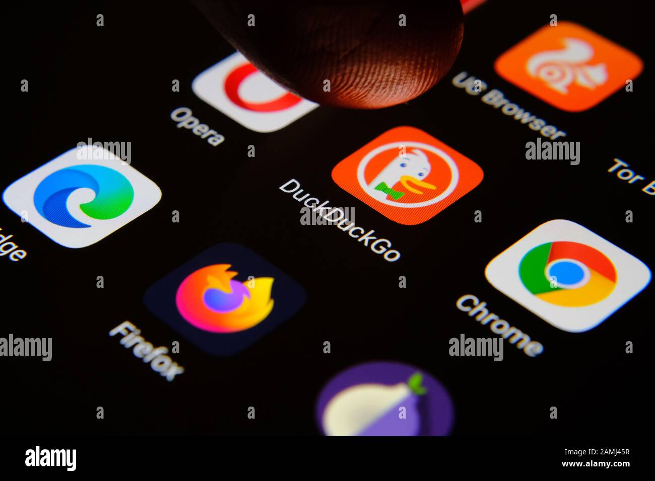 DuckDuckGo internet browser app surrounded by competitors and finger of user selecting it. Concept for competition. Macro photo. Stock Photo
