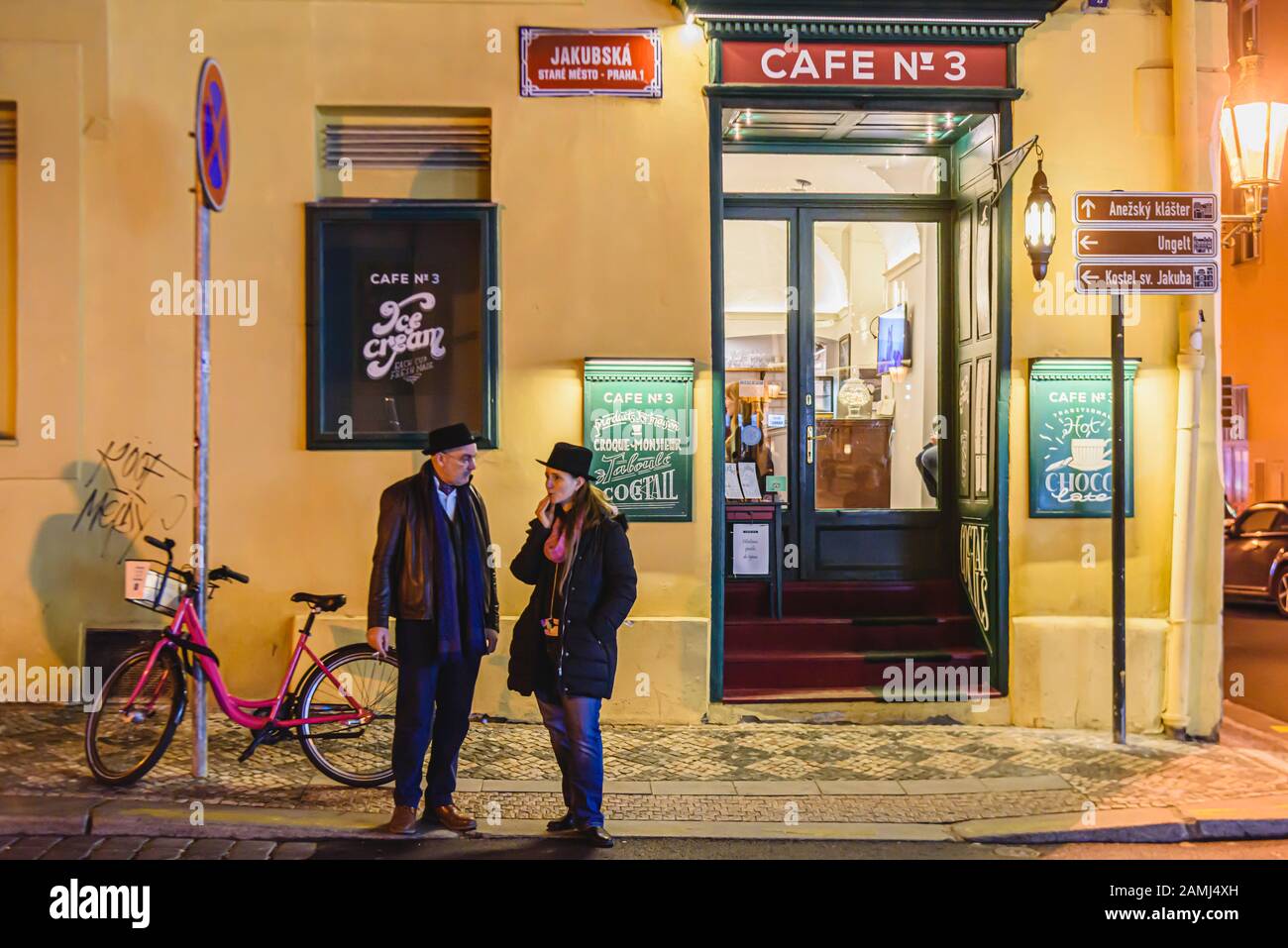 Two people standing outside a cafe at night while they have a cigarette, Prague, Czech Republic Stock Photo