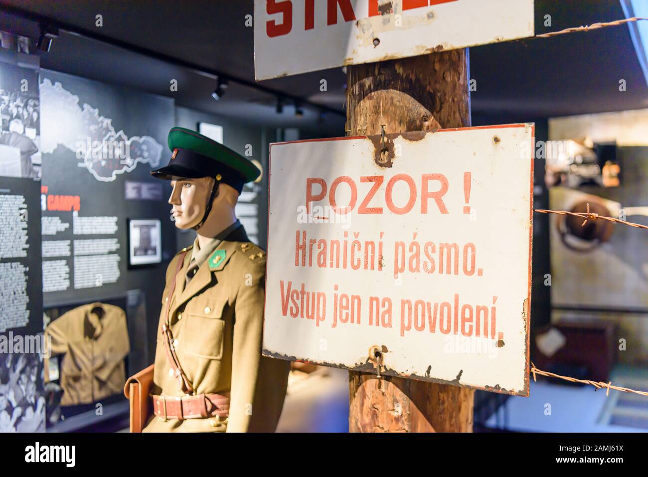 Warning signs in Czech on a barbed wire fence in a museum beside a mannequin wearing a Soviet era military uniform. Stock Photo