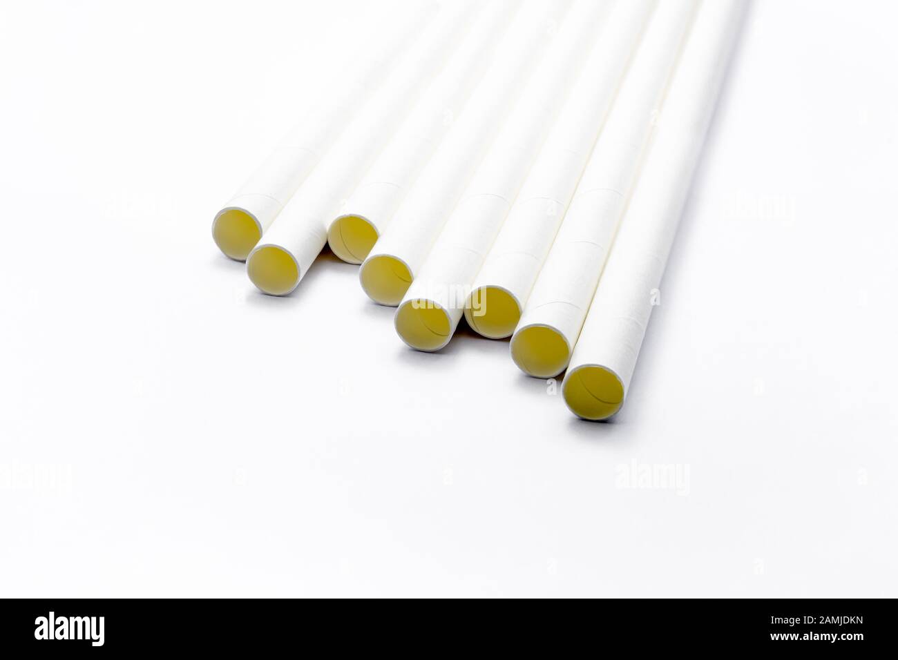 Close up white paper straws laying flat isolated on white background. Stock Photo