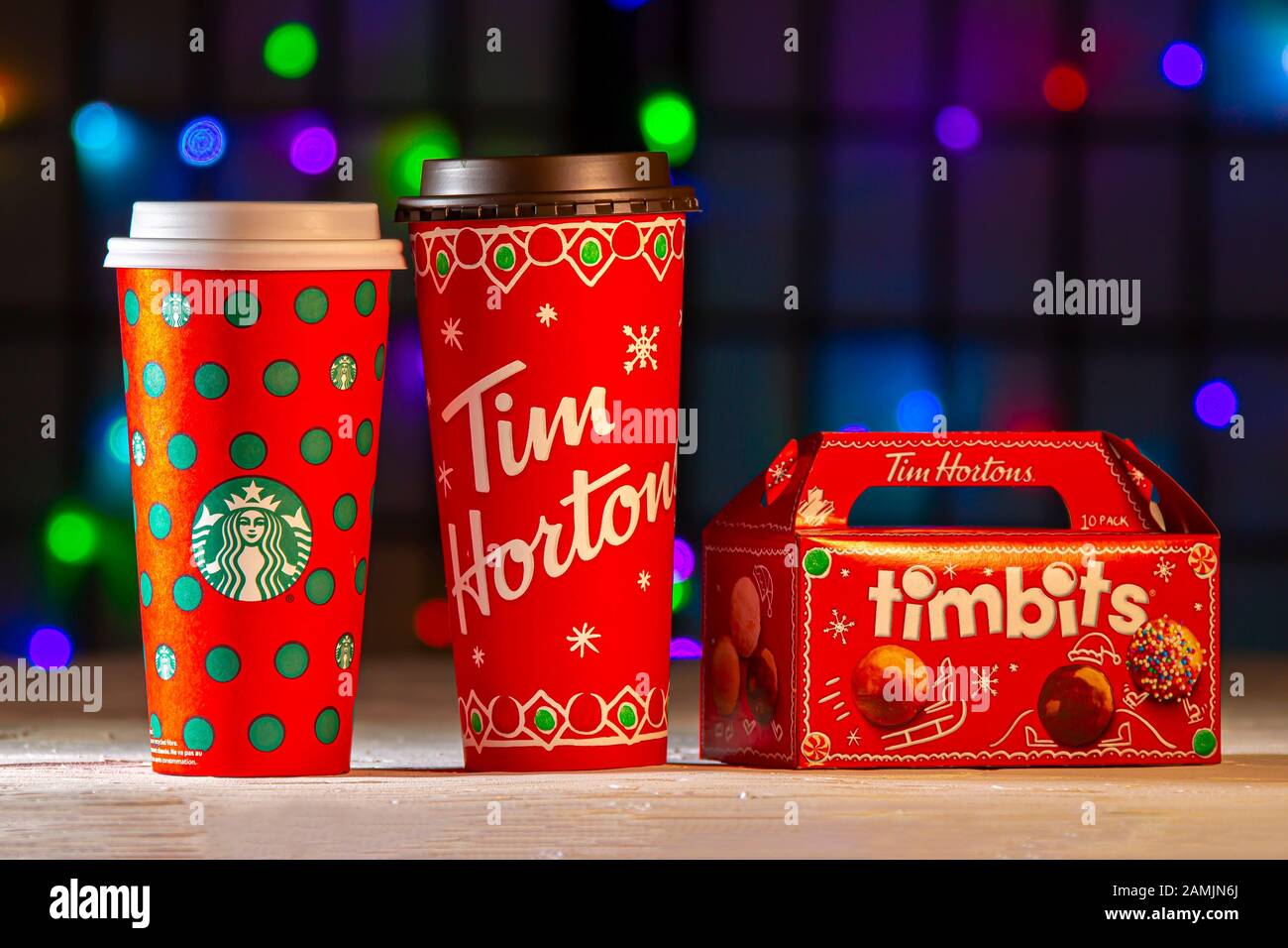 Calgary, Alberta, Canada. Jan 13, 2020. Christmas Starbucks and Tim Hortons coffee cups with some bite-sized fried-dough box with Christmas lights on Stock Photo