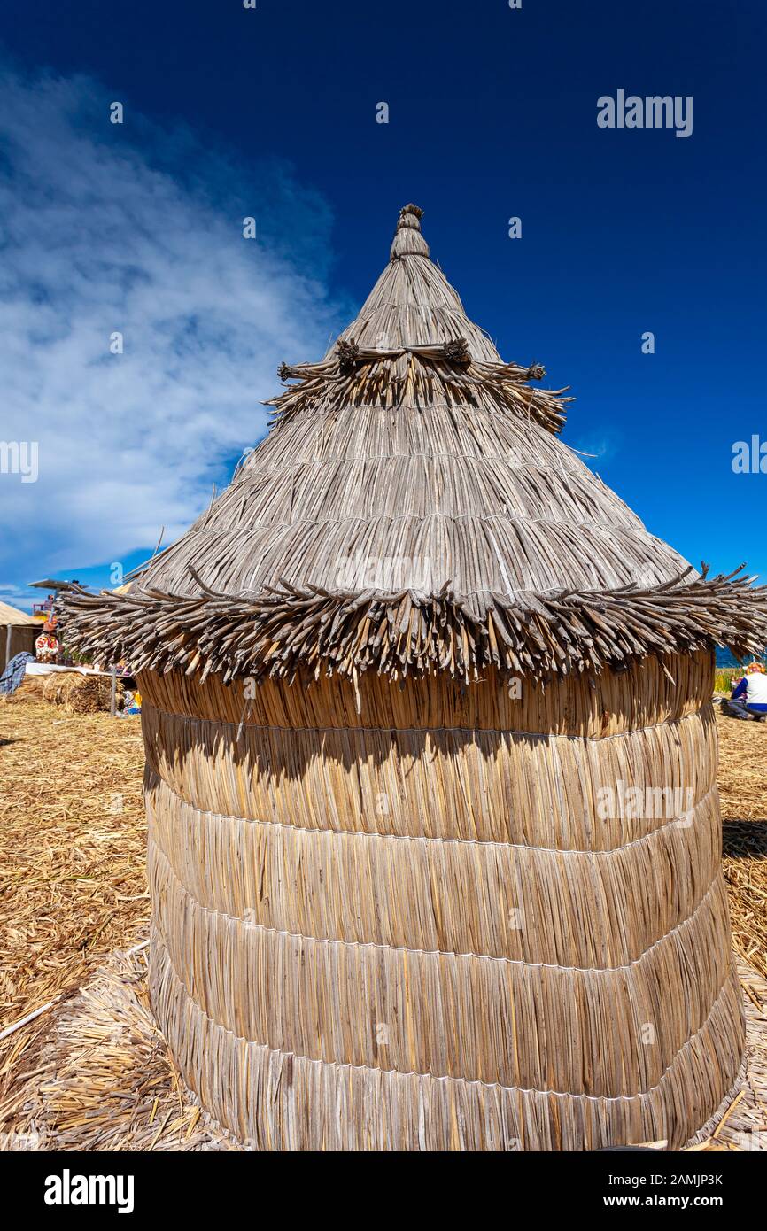 Traditional reed houses on floating Uros islands, at a distance, clouds