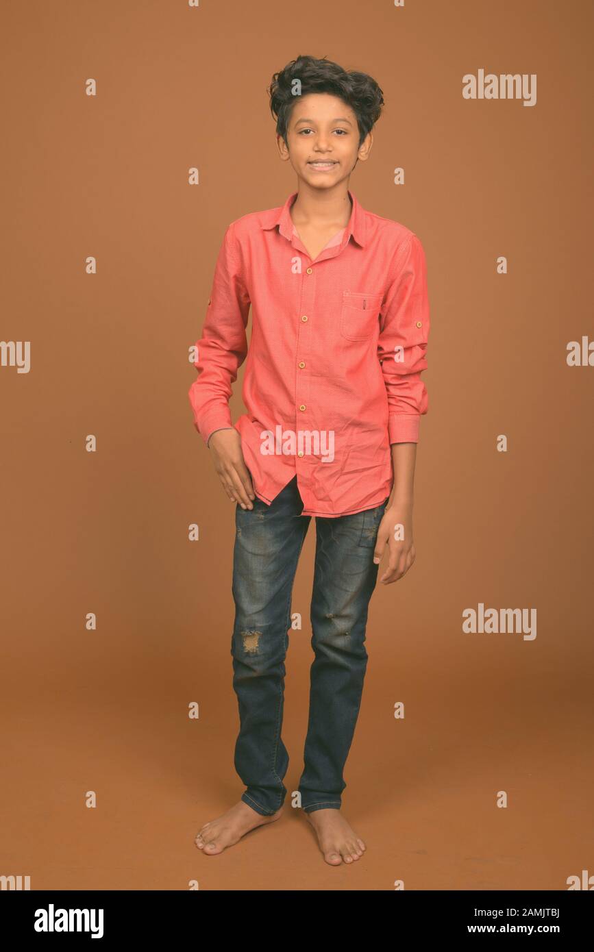 Studio shot of young Indian boy wearing smart casual clothing against brown background Stock Photo Alamy