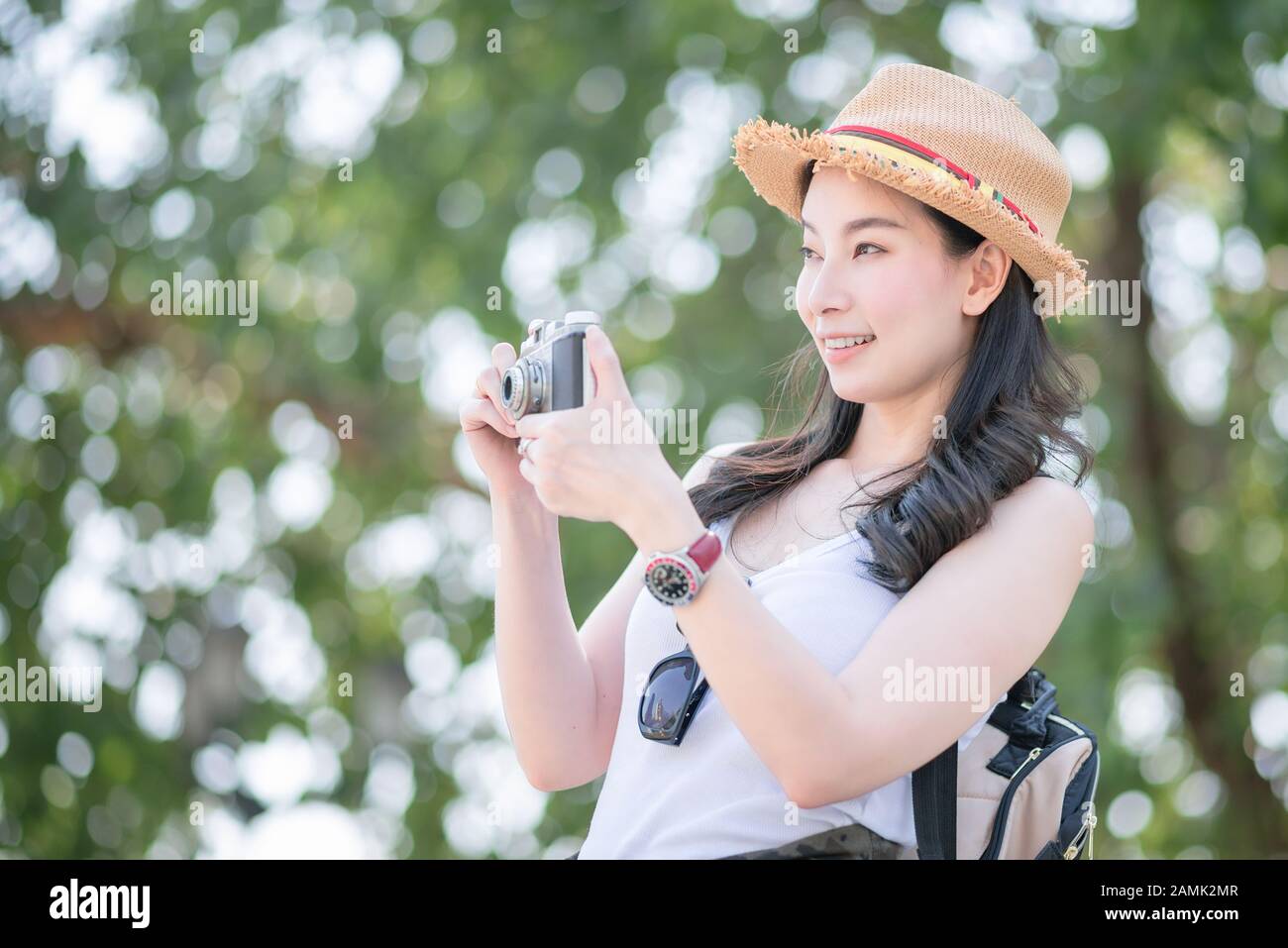 Beautiful asian tourist woman enjoy taking photo by retro camera at tourist sightseeing spot. Vacation travel in summer. Stock Photo