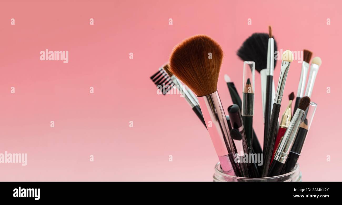 Make up brushes set against red background, top view. Professional tools for make up and art, beauty salon, cosmetics concept Stock Photo