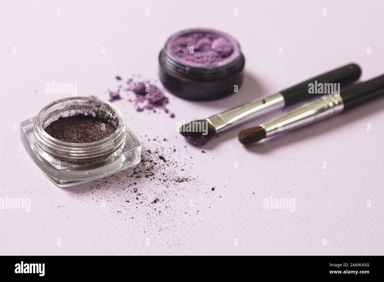 Eyeshadow purple color and brushes against pink background, closeup view. Professional tools for make up, beauty salon, cosmetics concept Stock Photo