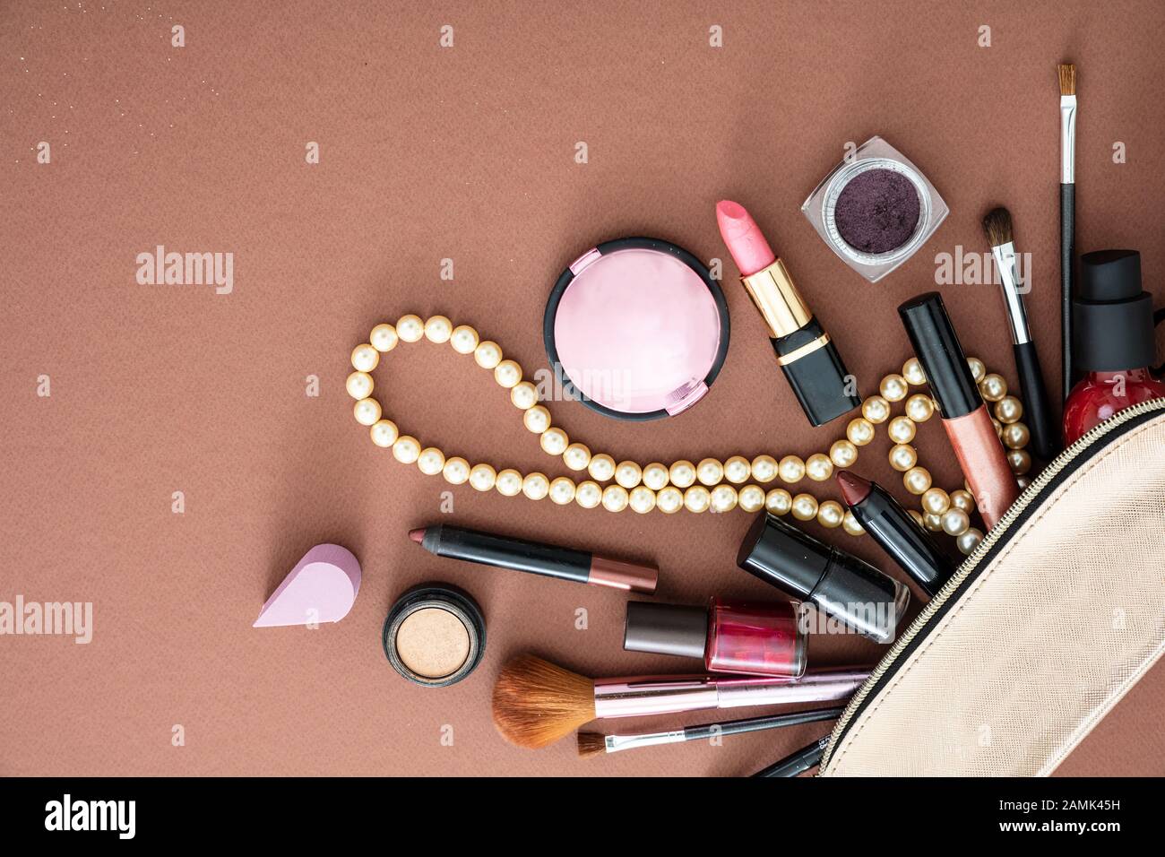 Make up cosmetic bag with professional accessories. Lipsticks and brushes  out of a gold cosmetic bag against brown color background, copy space Stock  Photo - Alamy