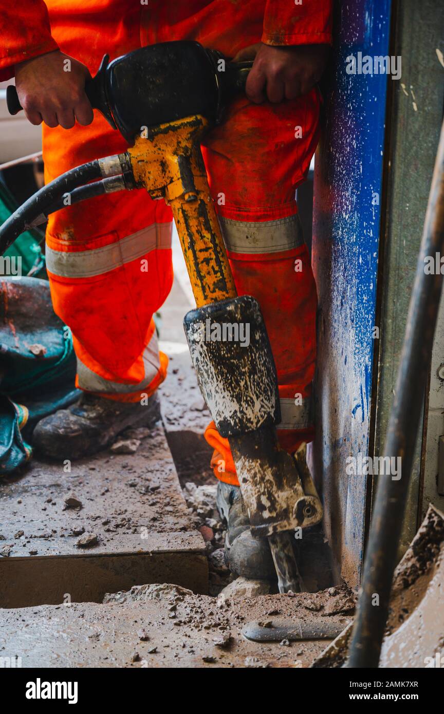 Man working breaking concrete with full Saftey gear and ppe, jack hammer, hi vis, hands, strong, Stock Photo