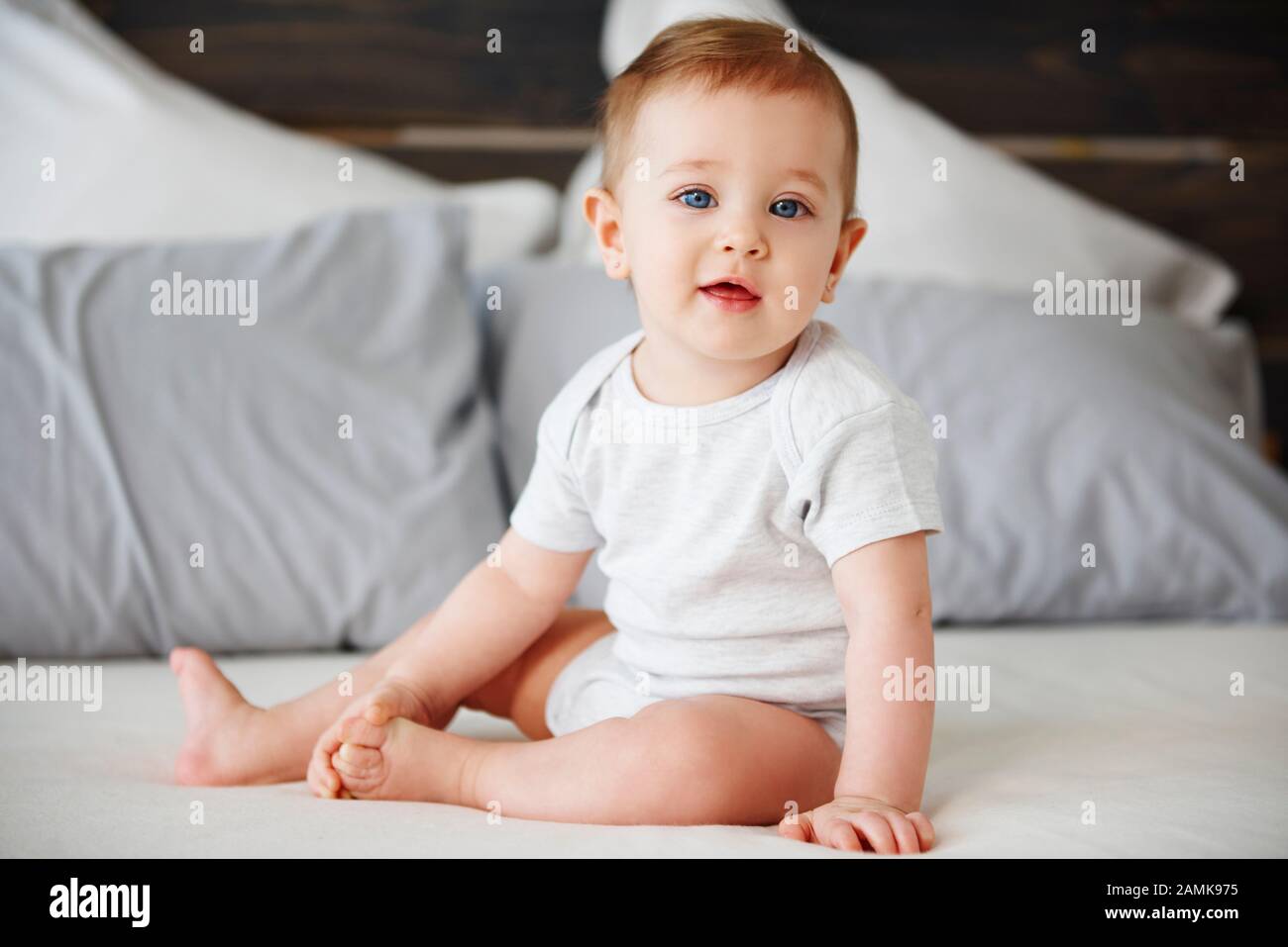 Portrait of cute baby sitting on bed Stock Photo