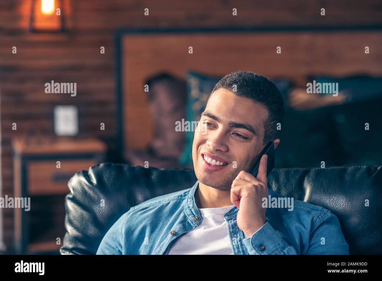 Handsome guy talking on a smartphone while at home. Stock Photo