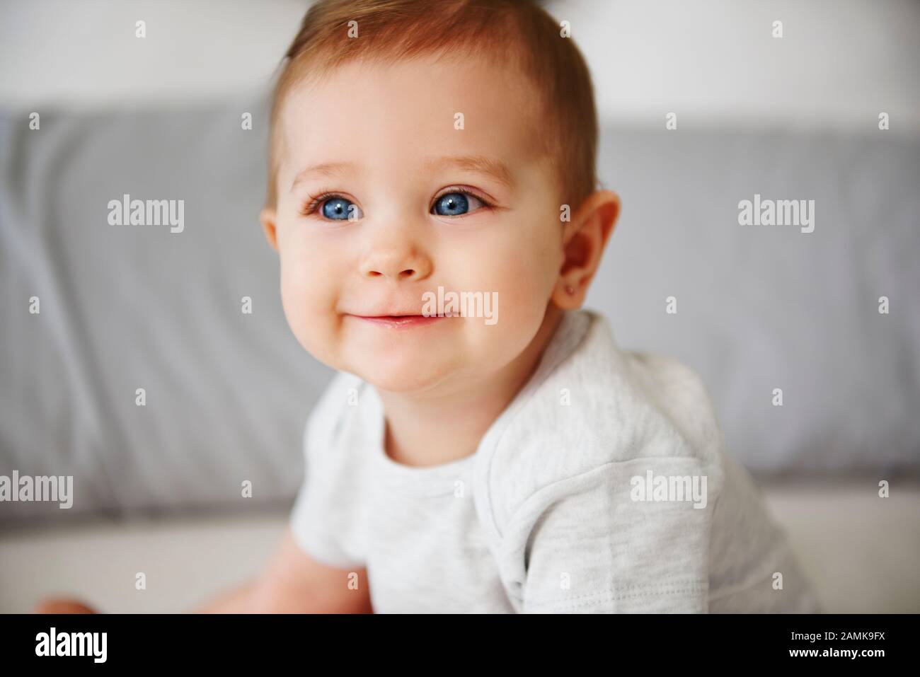 Close up of charming baby sitting on bed Stock Photo