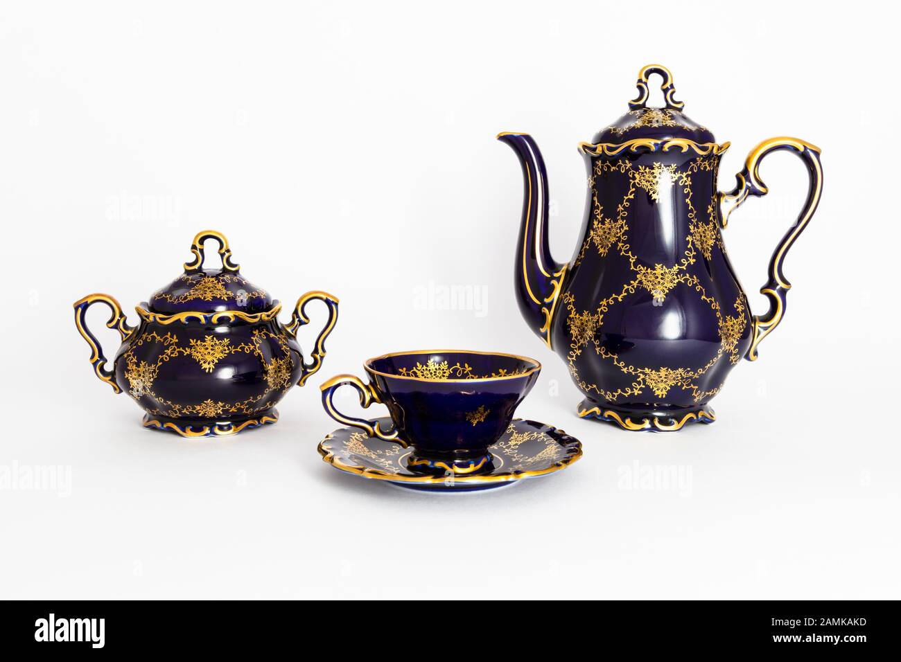 Closeup of a beautiful cobalt blue colored vintage porcelain tea set with golden floral pattern on white background. The set includes a tea pot, a sug Stock Photo